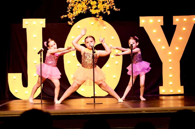 young dancers on stage with JOY written big in background